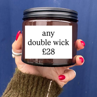Hand holding a candle jar with 'any double wick £28' text against a blue background